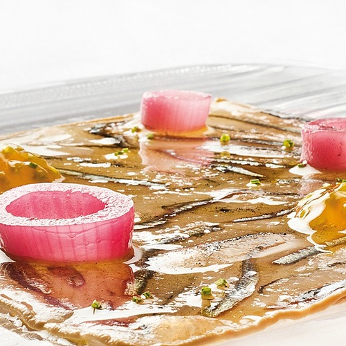 Il 'Quadro di alici marinate con acqua di mare' nasce come una necessità, perché Pino Cuttaia era stanco di vedere le acciughe marinate con i forti aceto e limone. Allora pensa di utilizzare la tecnica dei marinai siciliani quando stanno più giorni in mare: aggiungono al pesce appena pescato l’acqua di mare e il ghiaccio. Per dare un leggero sapore d’affumicatura, usa il carbone di nero di seppia. La cornice di questo magnifico quadro è ottenuta con una maionese di bottarga di tonno mentre la cipolla e i semi di pomodoro servono a rinfrescare e a detergere la bocca. - Piatti: Quadro di alici marinate